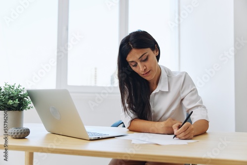 A woman works and learns by writing down text on paper with a pen and checking for errors, studying and teaching in college, business work