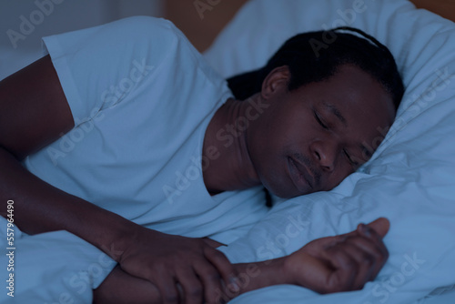 Portrait Of Young African American Man Sleeping In Bed During Night Time