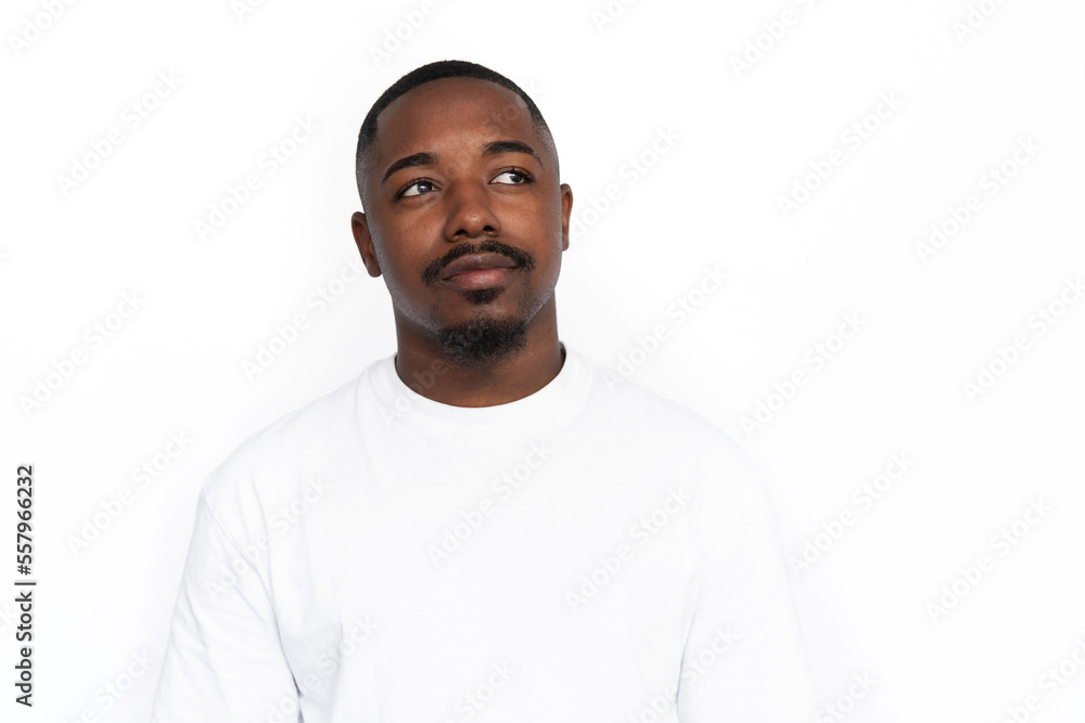 Confused African American man looking away. Portrait of unsure young male model with short hair in white T-shirt looking at ads, cocking eyebrow. Doubt, advertising concept