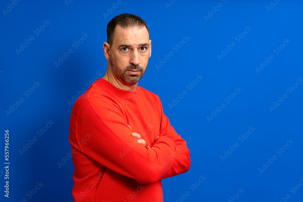 Portrait of a serious casual man standing with his hands crossed isolated on a blue background. Portrait of a serious casual man standing with his hands crossed isolated on a blue background.