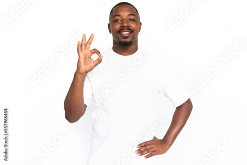 Confident African American man showing ok sign. Portrait of happy young male model with short hair in white T-shirt looking at camera, smiling, approving message or product. Advertising concept