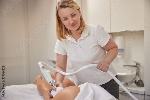 beauty clinic, Correction figures, roller massage. Young woman is taking part in beauty consultations, body shaping within professional beauty salon, masseur is using vacuum roller massage for client