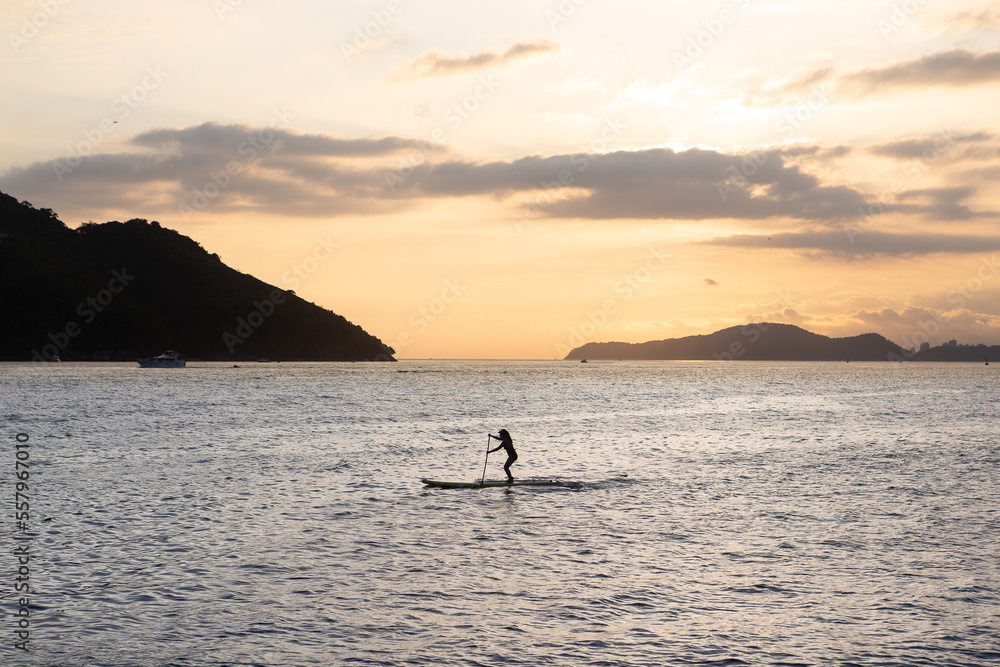 Girl practicing stand up paddle during the late afternoon in Santos bay Girl practicing stand up paddle during the late afternoon in Santos bay