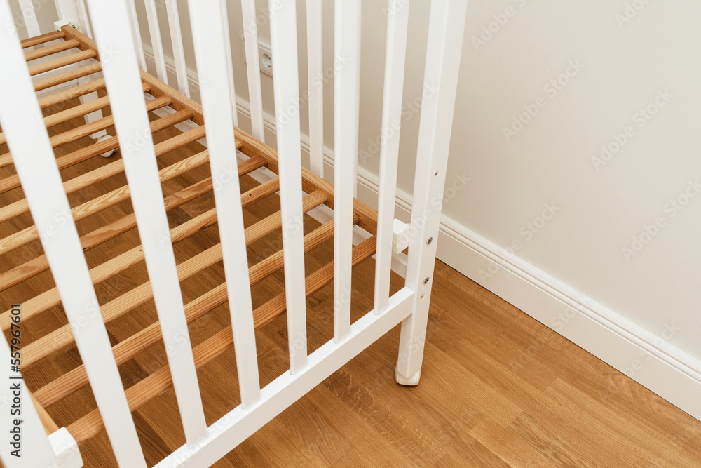Detail close-up of new crib without mattress in nursery room - relocation baby arrival preparation concept Detail close-up of new crib without mattress in nursery room - relocation baby arrival preparation concept