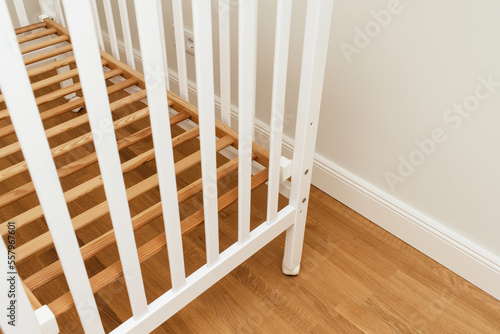 Detail close-up of new crib without mattress in nursery room - relocation baby arrival preparation concept