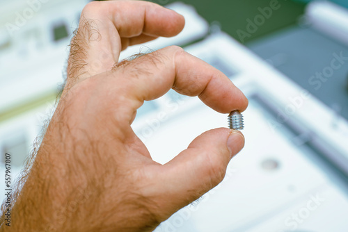 Man holding metallic screw with defocused furniture assembling background