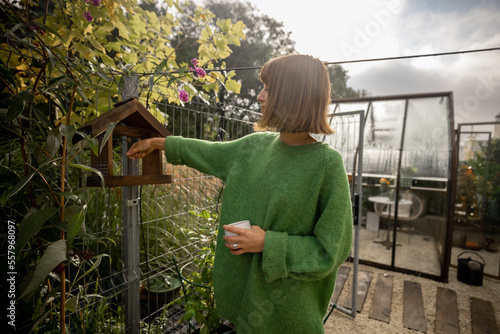 Photography Woman pours food for birds into a feeder in her yard, taking care of birds and s