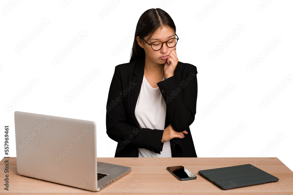 Young business asian woman sitting on a table isolated who feels sad and pensive, looking at copy space. Young business asian woman sitting on a table isolated who feels sad and pensive, looking at copy space.