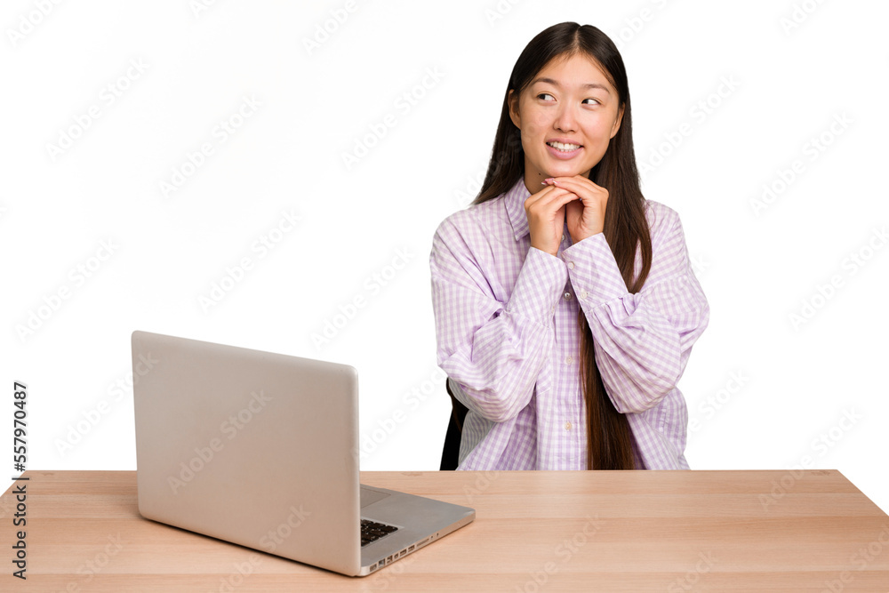 Young student asian woman in a workplace with a laptop isolated keeps hands under chin, is looking happily aside. Young student asian woman in a workplace with a laptop isolated keeps hands under chin, is looking happily aside.
