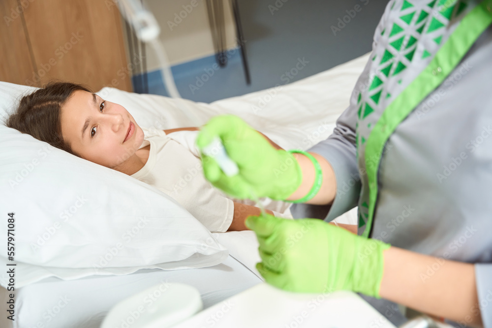 Nurse at the workplace corrects the dropper to a little patient Nurse at the workplace corrects the dropper to a little patient