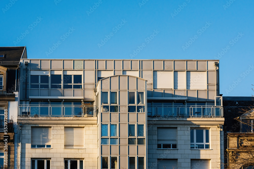 Warm sun over modern French apartment building with balconies terrace and clear blue sky in background