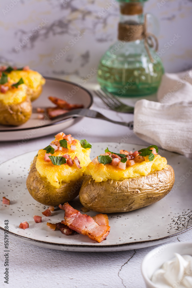 Twice baked potatoes with bacon and cheese on a plate on the table. Homemade dinner. Vertical view