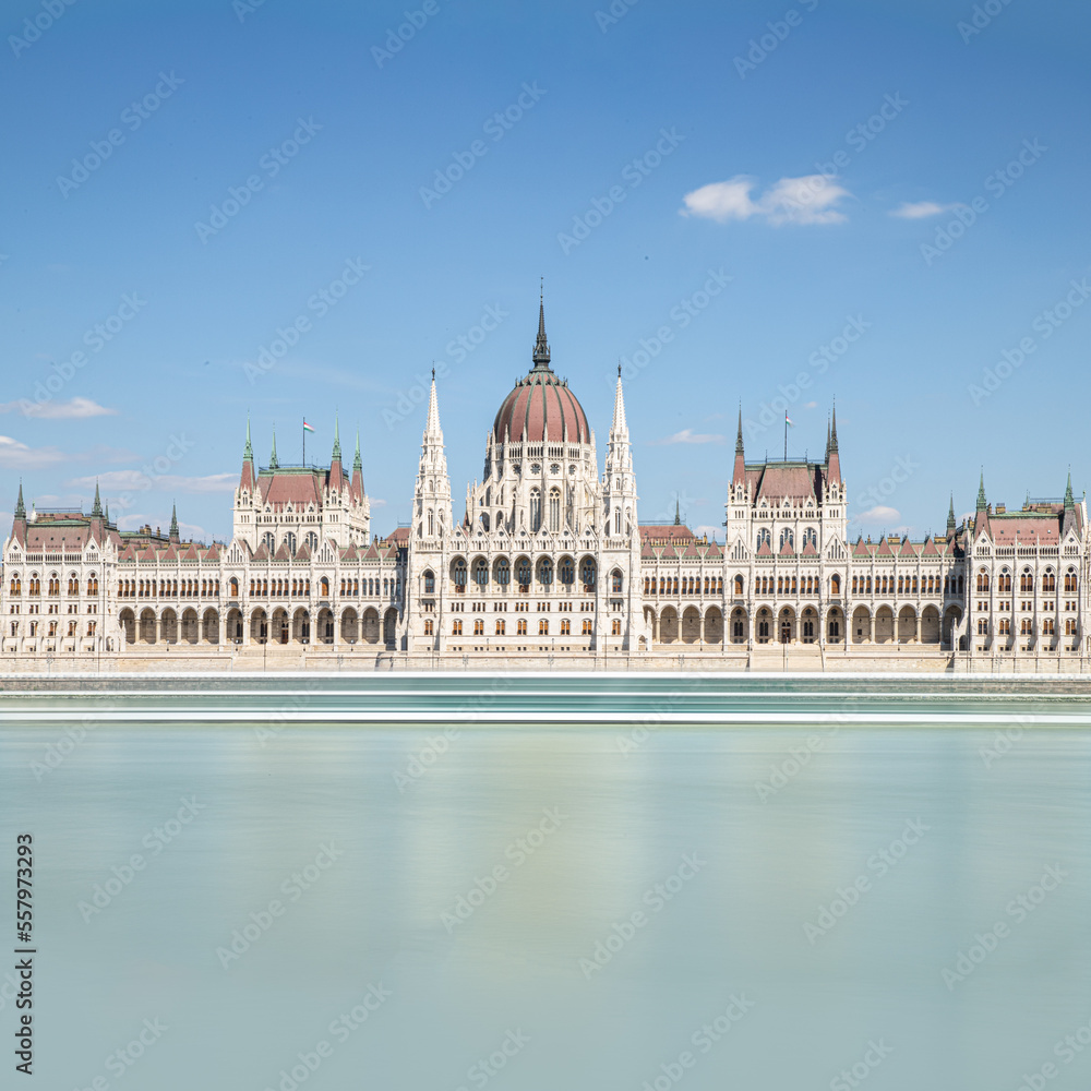 Fototapeta premium Hungarian parliament building on Danube, Budapest, long exposure square, clear blue sky, blurred water