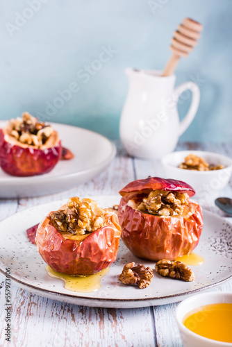 Whole baked apples with honey and walnuts on a plate. Homemade dessert. Vertical view