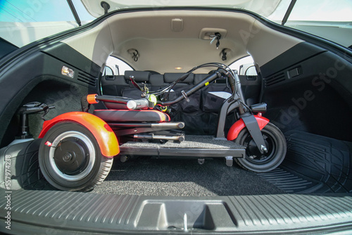 Electric wheelchair or foldable three wheels mobility scooter in the car trunk. Mobility means for people with disability or mobility issues. Freedom of movement and daily life independence.
