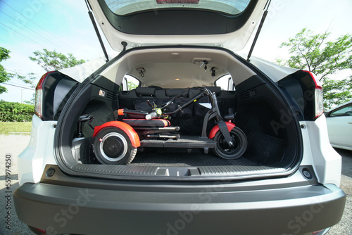 Electric wheelchair or foldable three wheels mobility scooter in the car trunk. Mobility means for people with disability or mobility issues. Freedom of movement and daily life independence.