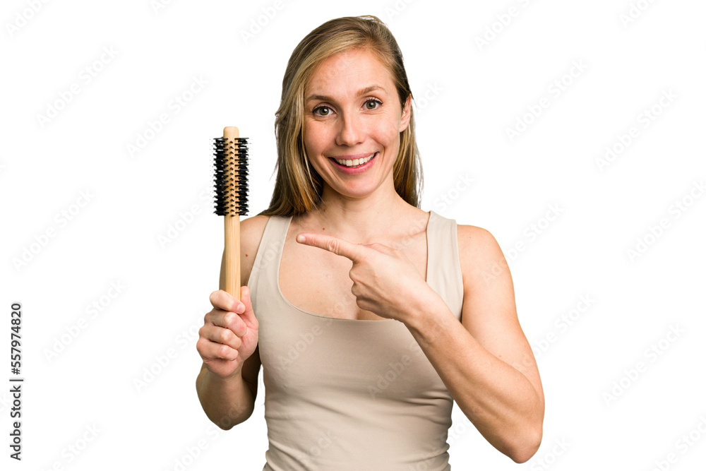 Young caucasian woman using an hair comb isolated smiling and pointing aside, showing something at blank space. Young caucasian woman using an hair comb isolated smiling and pointing aside, showing something at blank space.