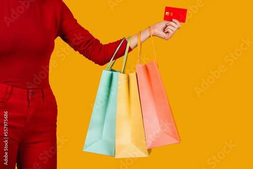Unrecognizable woman in red holding shopping bags and credit card