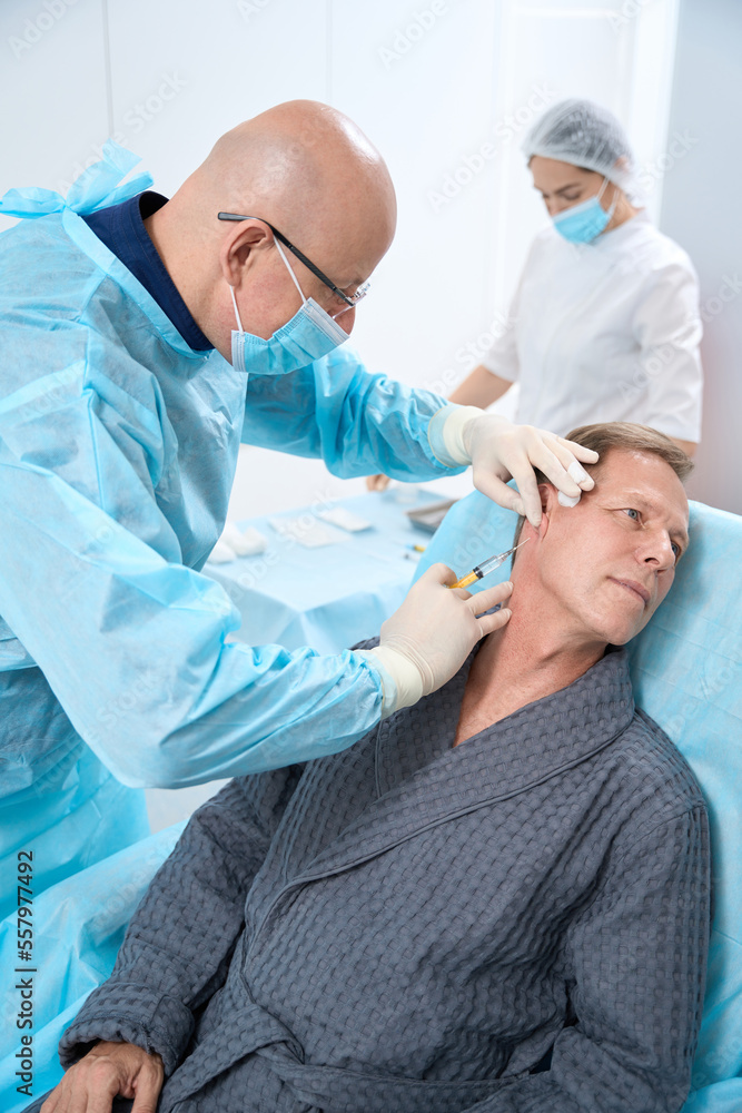 Mature patient not moving while receiving an injection from doctor Mature patient not moving while receiving an injection from doctor