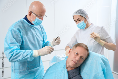 Doctor and nurse in sterile outfits holding equipment for suturing © Svitlana