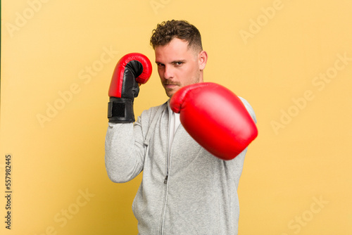 Adult man boxing isolated on yellow background © Asier
