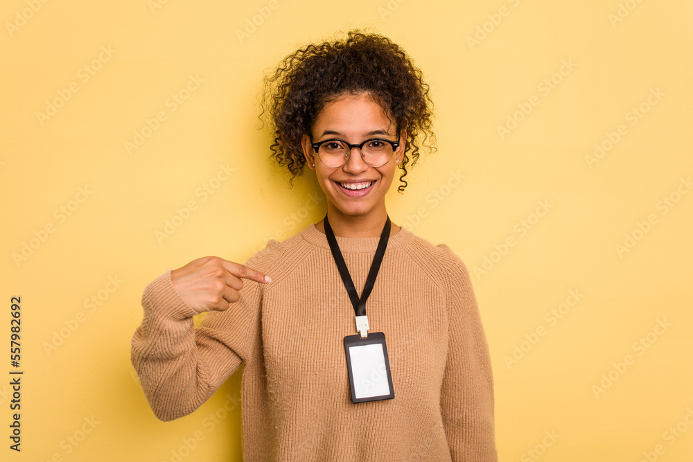 Young brazilian woman with a badge isolated on yellow background person pointing by hand to a shirt copy space, proud and confident - obrazy, fototapety, plakaty 