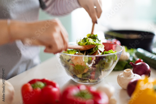 Female hands making fresh vegetable salad  preparing meal at home