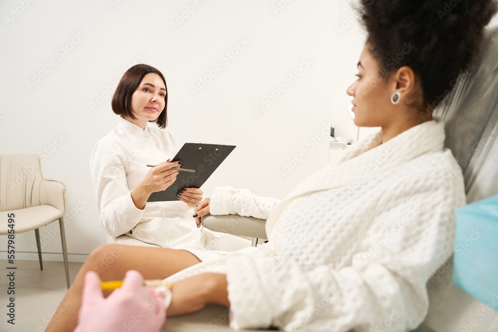 Two doctors consulting lady in beauty salon during procedure Two doctors consulting lady in beauty salon during procedure