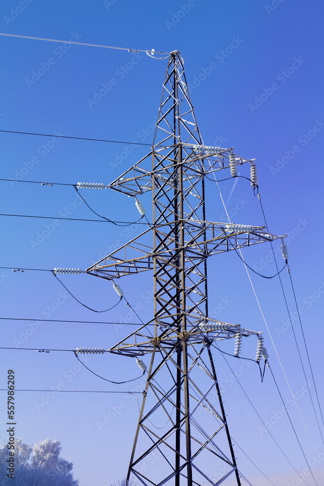 Frost-covered power line pylon on a clear frosty day against a blue sky Frost-covered power line pylon on a clear frosty day against a blue sky