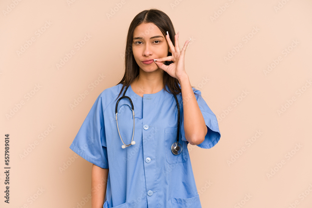 Young nurse colombian woman isolated with fingers on lips keeping a secret. Young nurse colombian woman isolated with fingers on lips keeping a secret.