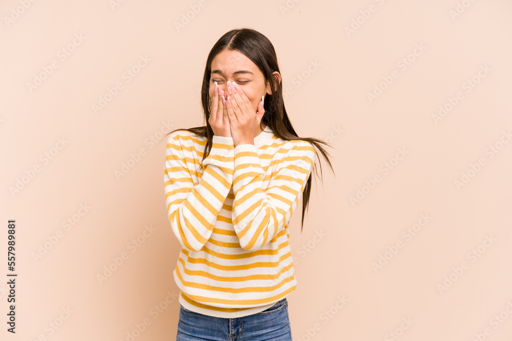 Young colombian woman isolated on beige background laughing about something, covering mouth with hands. Young colombian woman isolated on beige background laughing about something, covering mouth with hands.