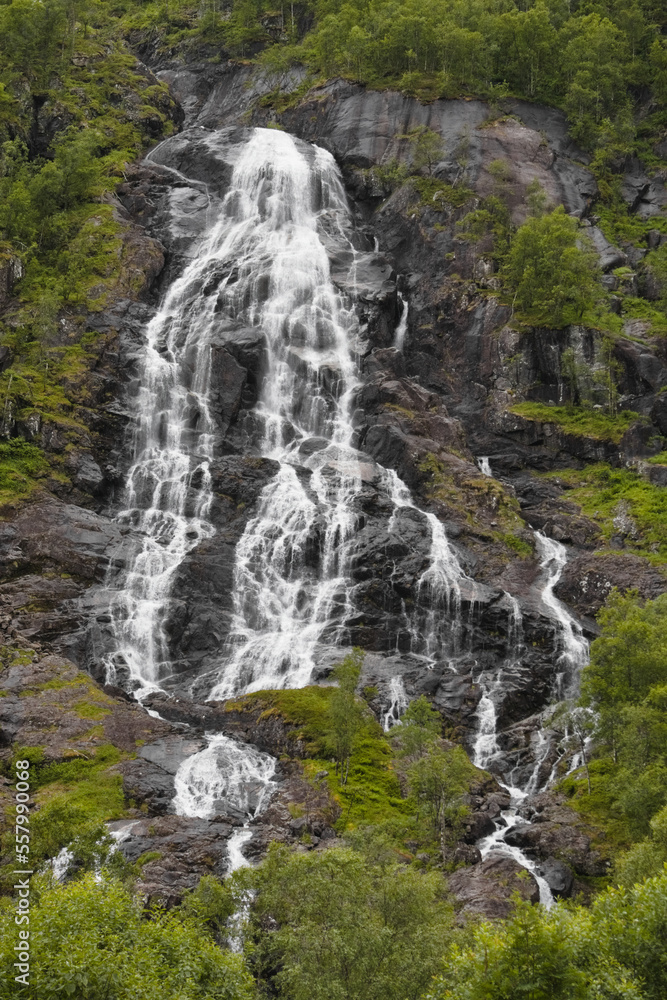 Obraz premium A beautiful waterfall in the forest with several smaller streams flowing over the rocks.