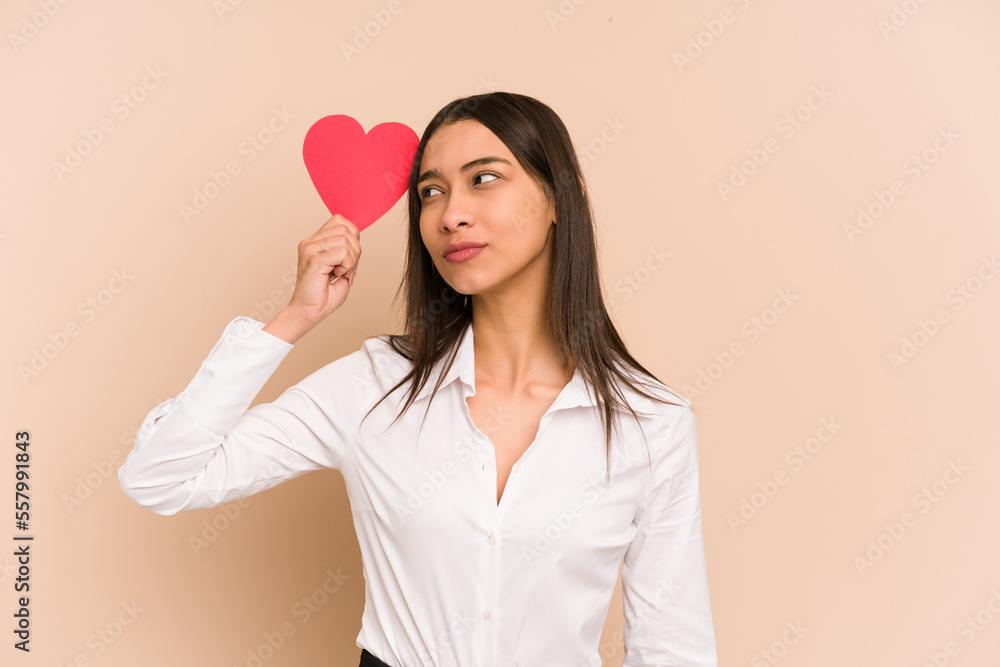 Young colombian woman holding a heart paper for valentines day isolated Young colombian woman holding a heart paper for valentines day isolated