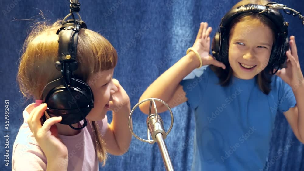 Two happy cheerful elementary school age girls in headphones singing