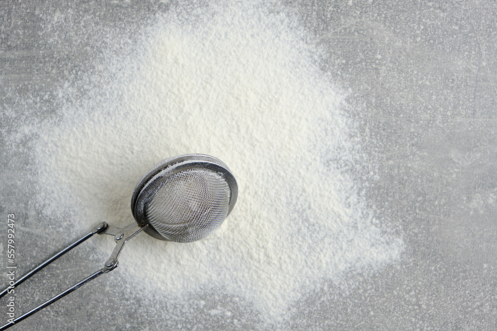 Cutlery, metal flour sieve and sifted flour on concrete background. Cutlery, metal flour sieve and sifted flour on concrete background.