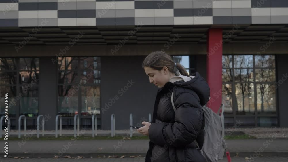 teenage girl in a black jacket with smartphone walking in the street in Wroclaw, Poland teenage girl in a black jacket with smartphone walking in the street in Wroclaw, Poland