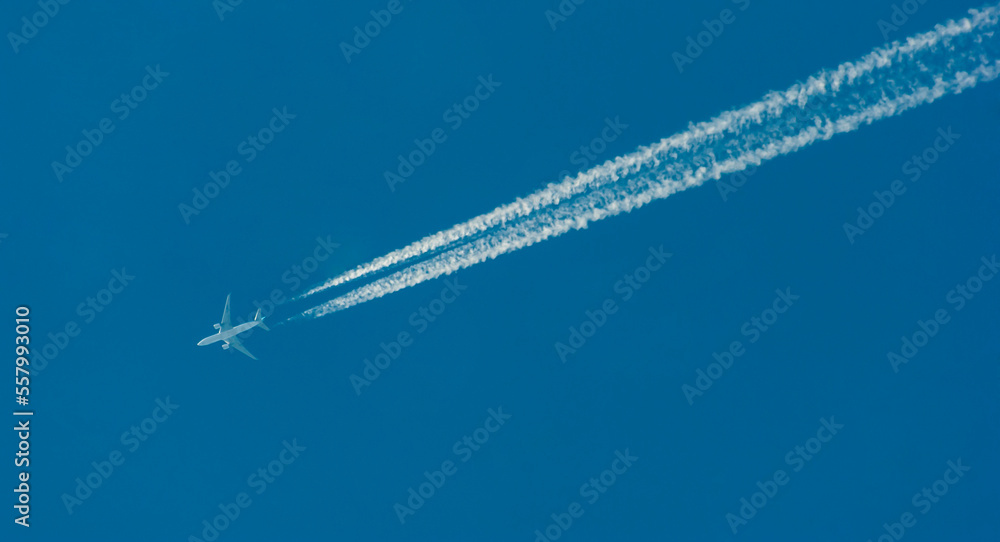 Pasażerski odrzutowiec przecinający błękit nieba , za samolotem potężne smugi kondensacyjne . - obrazy, fototapety, plakaty 