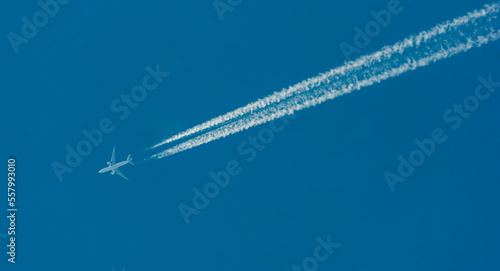 Pasażerski odrzutowiec przecinający błękit nieba , za samolotem potężne smugi kondensacyjne .
