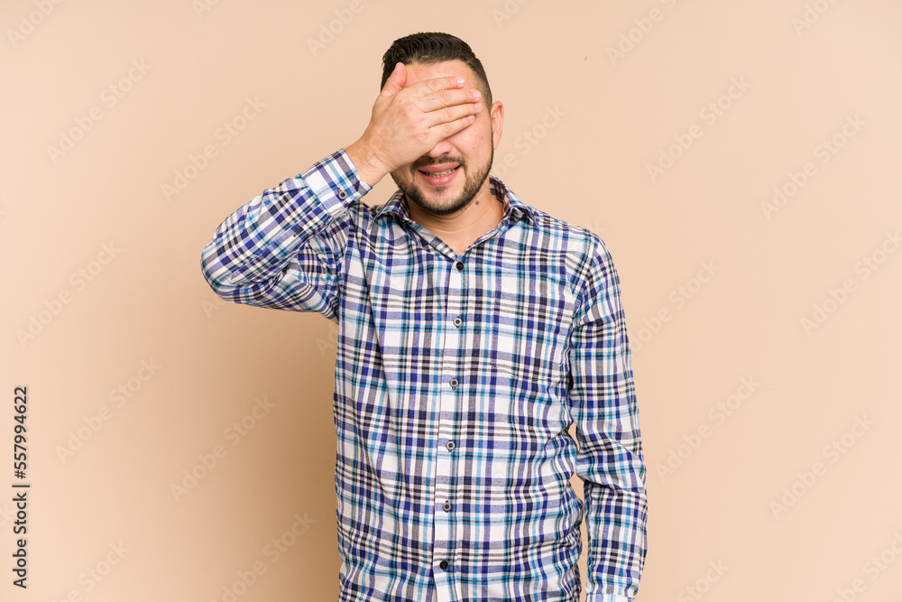 Adult latin man cut out isolated covers eyes with hands, smiles broadly waiting for a surprise.
