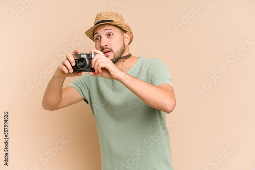 Adult latin man holding and using a vintage camera isolated