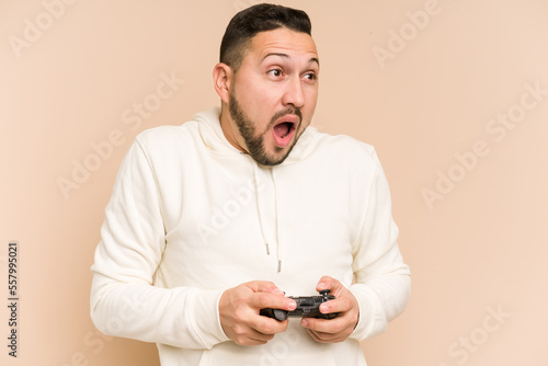 Adult latin man playing with a game controller isolated © Asier