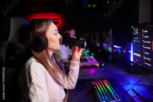 girl gamer sits at a computer and drinks an energy drink, a woman plays in a computer club at night and holds a drink © Богдан Маліцький