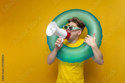 guy on vacation in the summer shouts and announces the news in a megaphone, man with an inflatable swimming circle