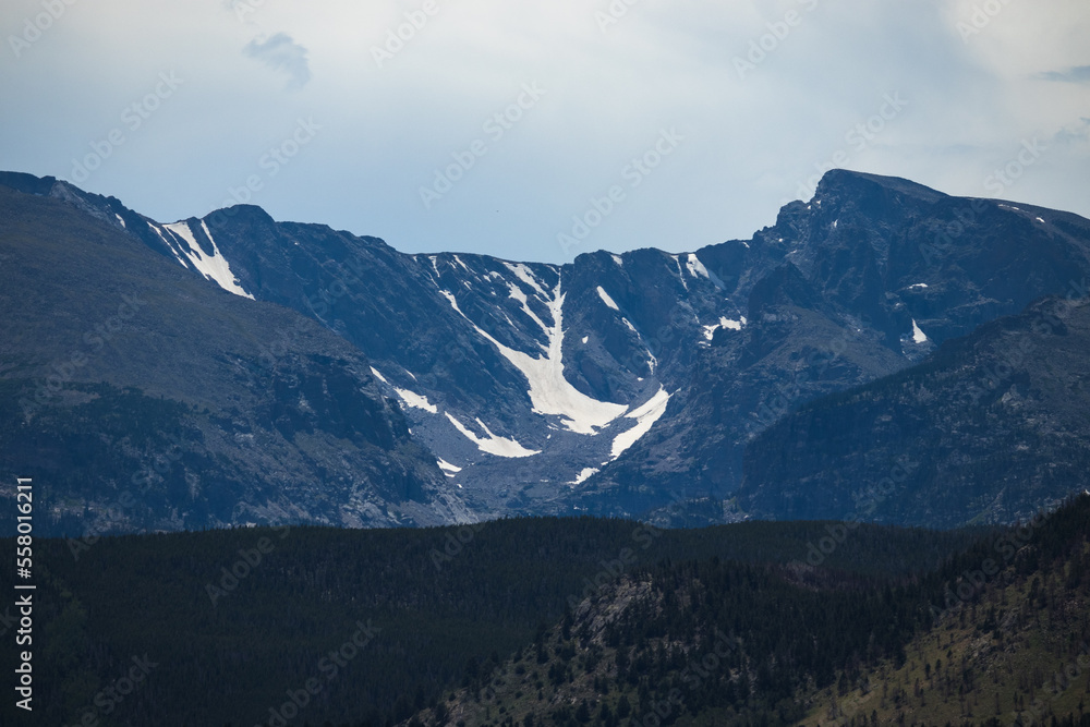 Snowy mountains surrounded by trees and rolling hills in Rocky Mountain National Park 