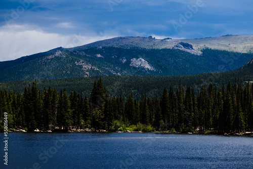 Fototapeta Naklejka Na Ścianę i Meble -  Bear Lake wooded shoreline with the Rocky Mountains in the distance, Colorado 