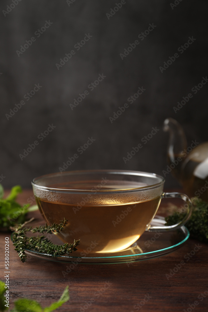 Cup of aromatic herbal tea and fresh thyme on wooden table Cup of aromatic herbal tea and fresh thyme on wooden table