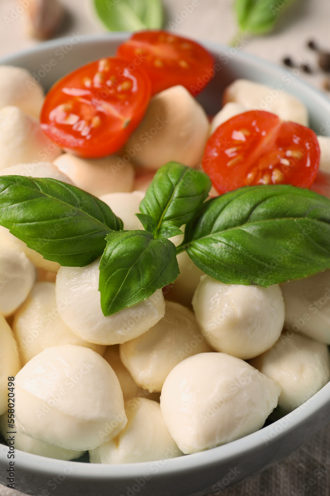 Delicious mozzarella balls, tomatoes and basil leaves in bowl on table, closeup Delicious mozzarella balls, tomatoes and basil leaves in bowl on table, closeup