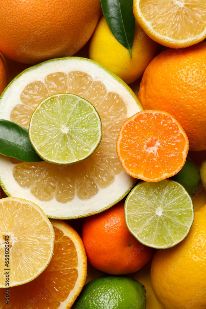 Different ripe citrus fruits with green leaves as background, top view Different ripe citrus fruits with green leaves as background, top view