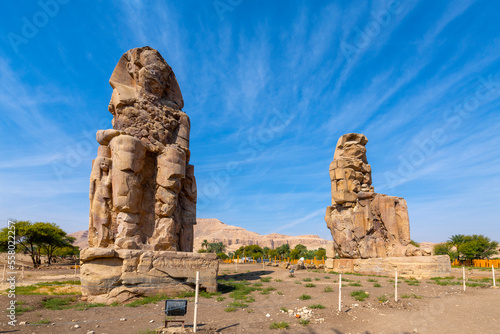 The ancient Egyptian Colossi of Memnon, two massive stone statues of the Pharaoh Amenhotep III, which stand at the front of the ruined Mortuary Temple of Amenhotep in Luxor, Egypt.
