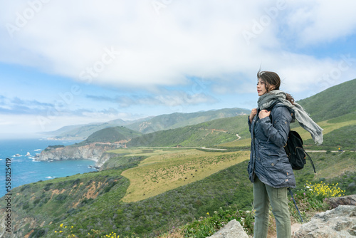 asian taiwanese woman backpacker overlooking scenic ocean and mountain view under blue sky while touring big sur in california usa